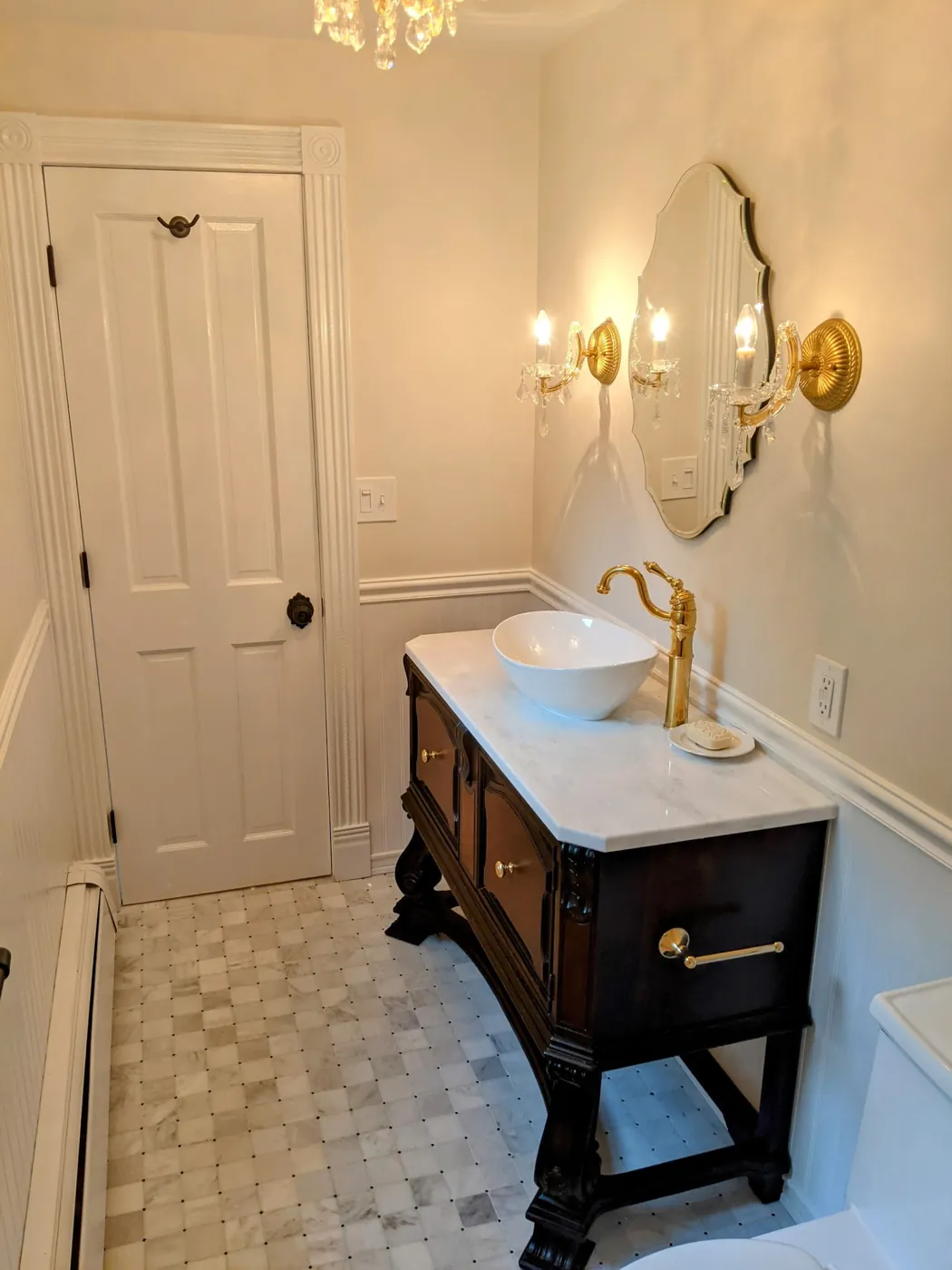 Hall bathroom remodel with an antique dark wood vanity, vessel sink, brass faucet, and marble basketweave tile floor in Monmouth County, NJ