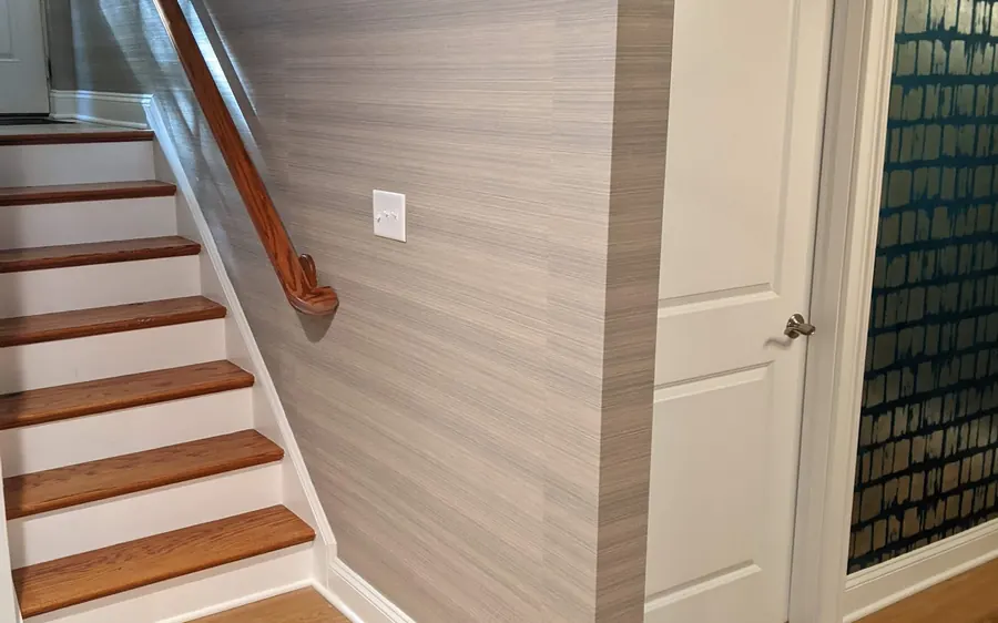 Interior renovation with a new oak staircase, painted railings, and textured wallpaper