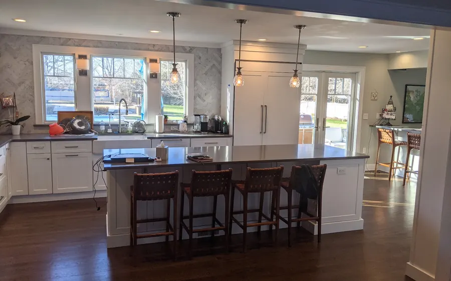 Kitchen remodel in Monmouth County, NJ with white shaker cabinets, a large island, and a stained wood range hood